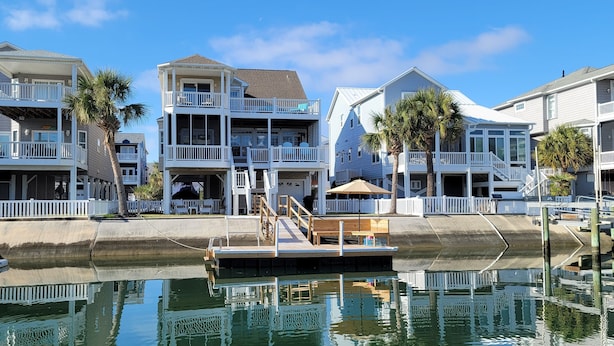 A waterfront property with multiple balconies, a dock, and a pool. - Canal home with access to the Intracoastal Waterway only steps from the beach! (Ocean Isle Beach)
