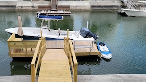 A dock with a boat and a smaller motorboat. - Canal home with access to the Intracoastal Waterway only steps from the beach! (Ocean Isle Beach)