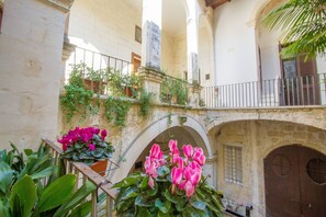 An interior courtyard with arches, a balcony, and potted plants. - Palazzo Sanseverino (Lecce)