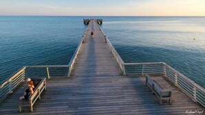 A wooden pier extending into calm waters with a clear sky. - Bel Appartement au Bord de L'océan (Saint-Jean-de-Monts)