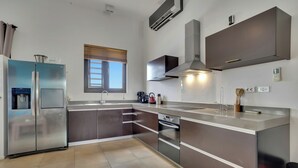 Una cocina moderna con electrodomésticos de acero inoxidable, horno empotrado y un amplio ventanal.