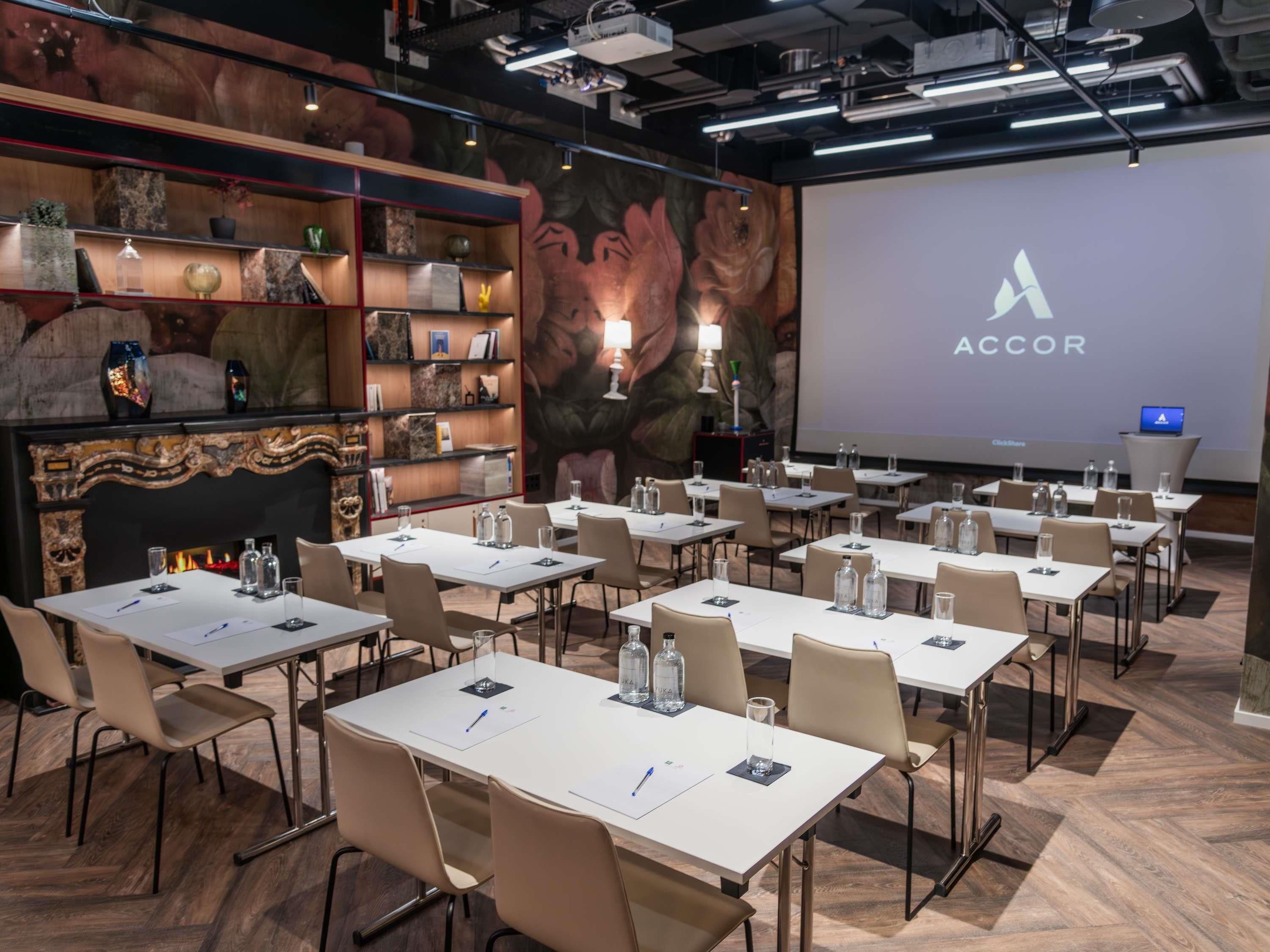 Une salle de conférence équipée de plusieurs tables, de chaises et d’un écran de présentation affichant le mot « ACCOR ».