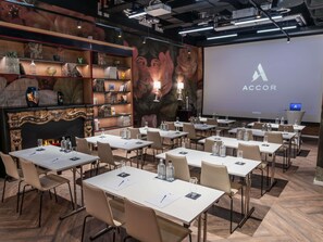 Une salle de conférence équipée de plusieurs tables, de chaises et d’un écran de présentation affichant le mot « ACCOR ».