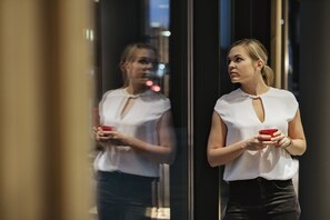 A person standing in front of a reflective surface, holding a red object. - Aparthotel Adagio Zurich Center (Zürich)