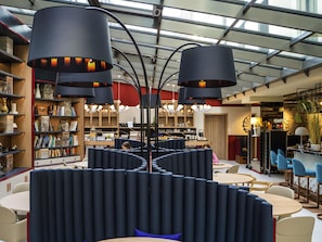 A modern interior with bookshelves, seating areas, and a bar. - Aparthotel Adagio Zurich Center (Zürich)