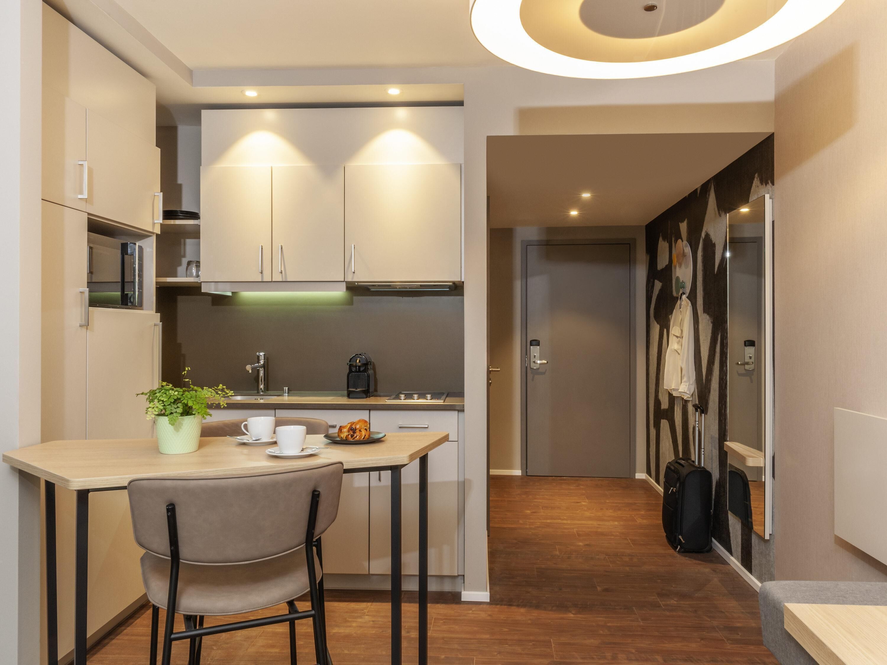 A compact kitchenette with a coffee machine, a small table, and a chair.