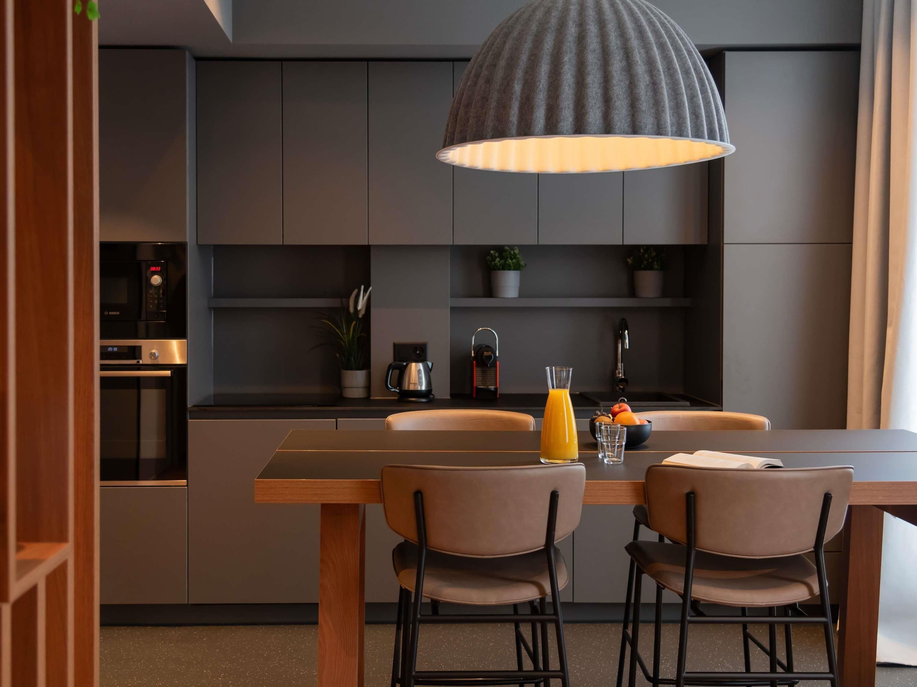 A modern kitchen with a dining table, chairs, and a pendant light.