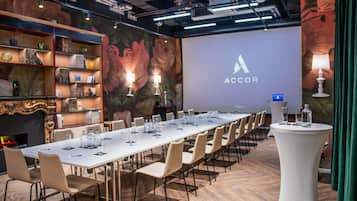 A conference room with a long table, chairs, a projector screen with ACCOR branding, and a decorative wall with floral patterns.