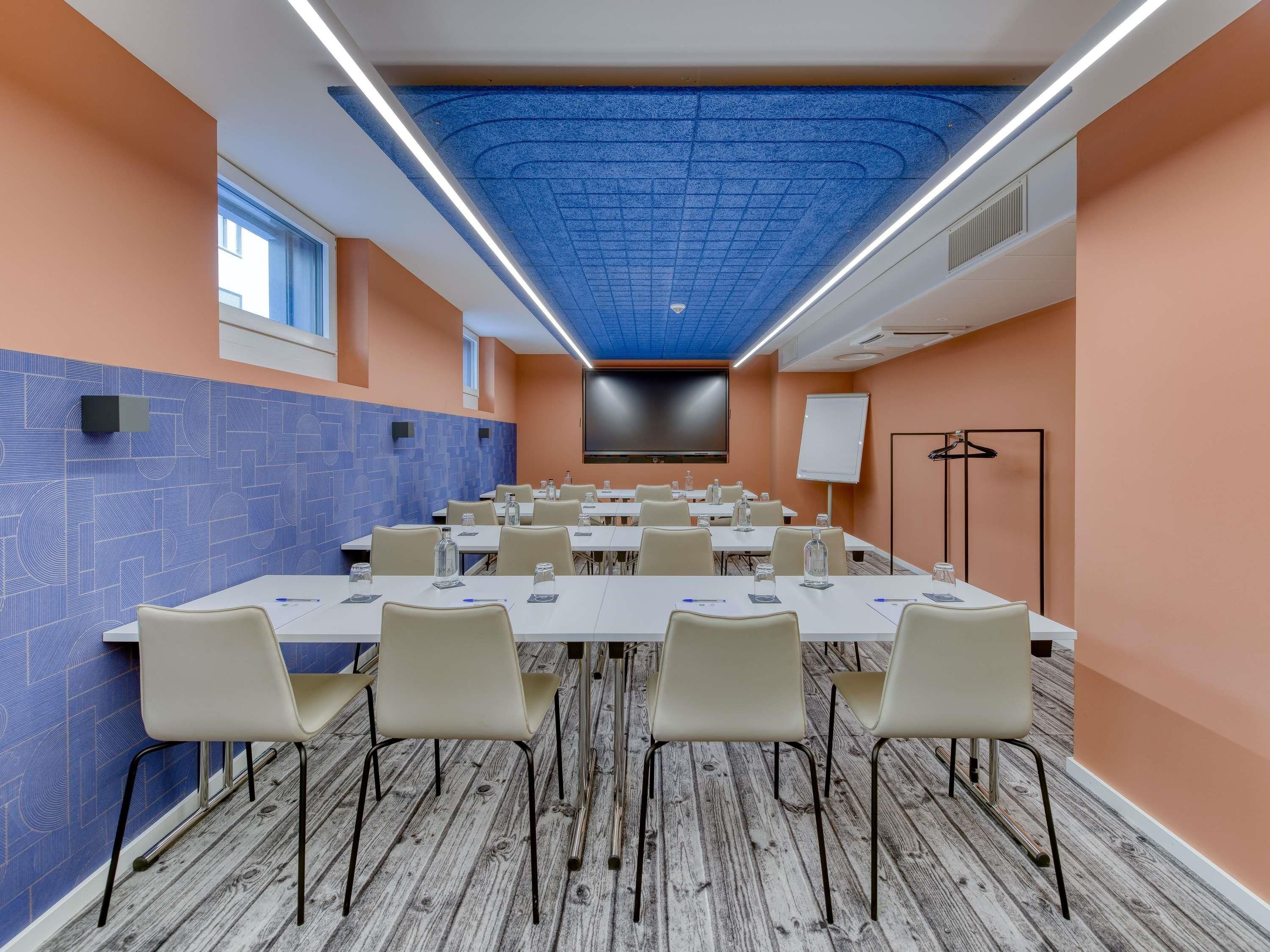 A conference room with a long table, chairs, a projector screen, and a whiteboard.