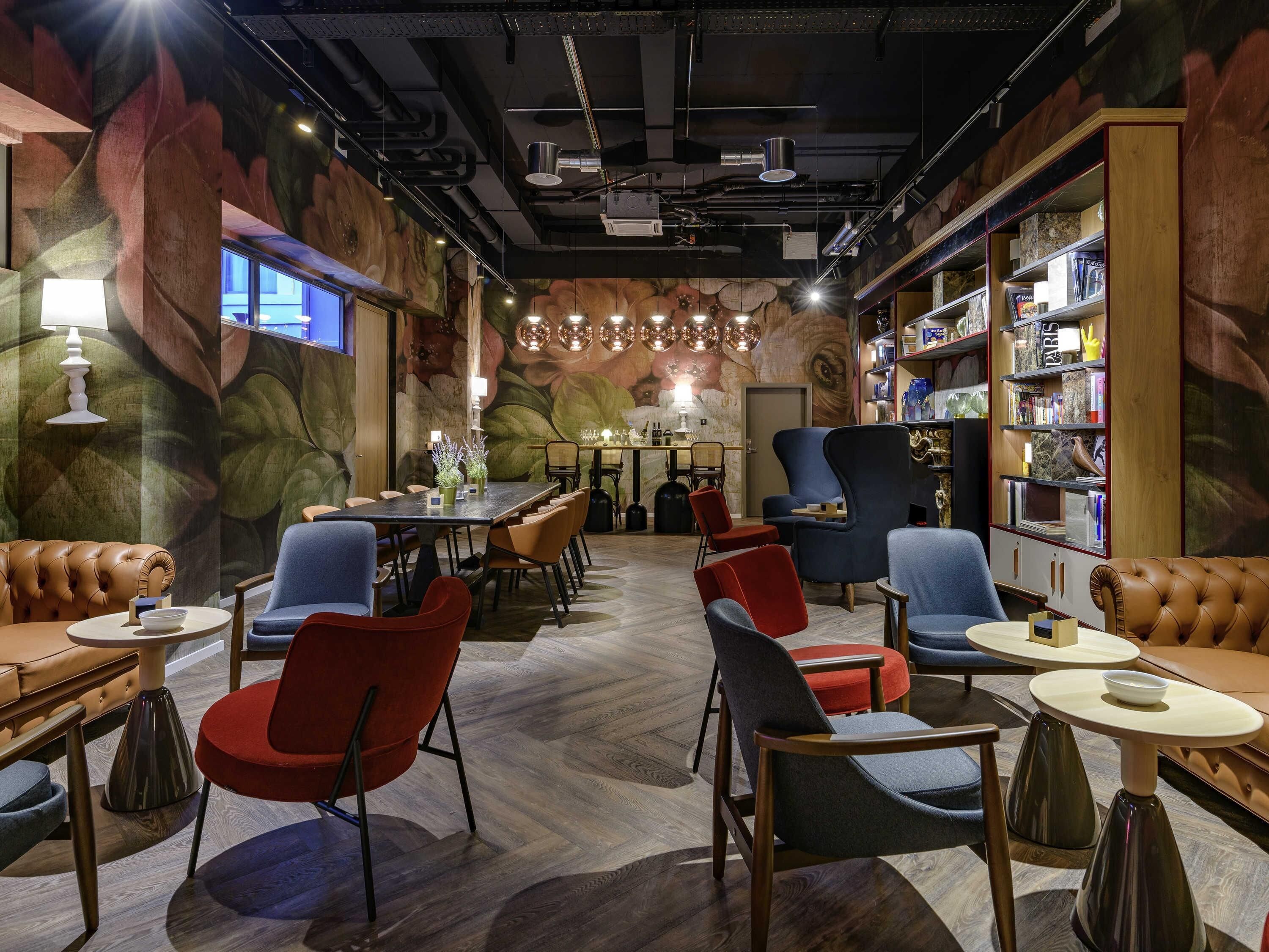 Un intérieur moderne avec une longue table à manger, de nombreuses chaises et une bibliothèque.