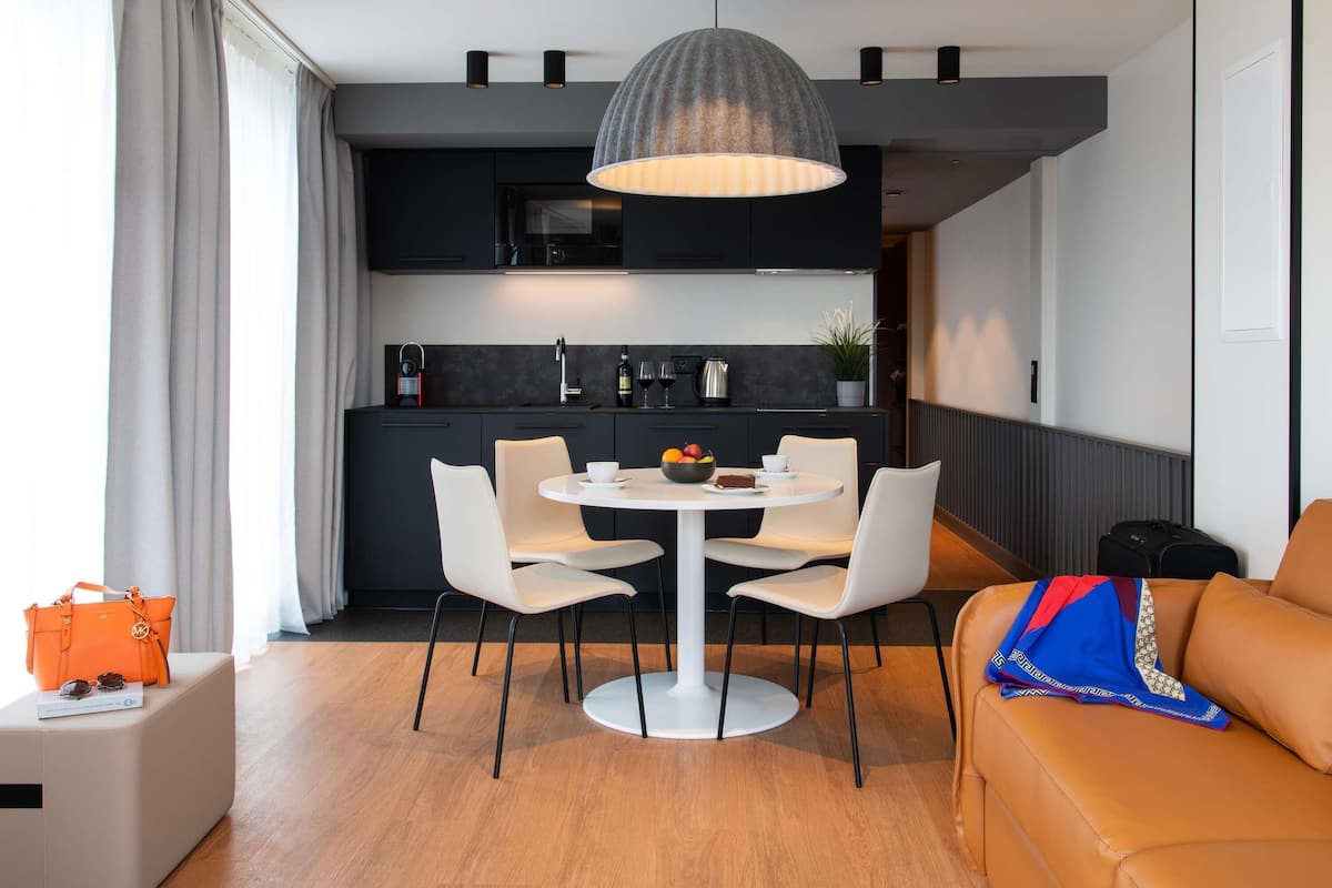 A modern kitchen with dark cabinets, a white dining table, and a pendant light.