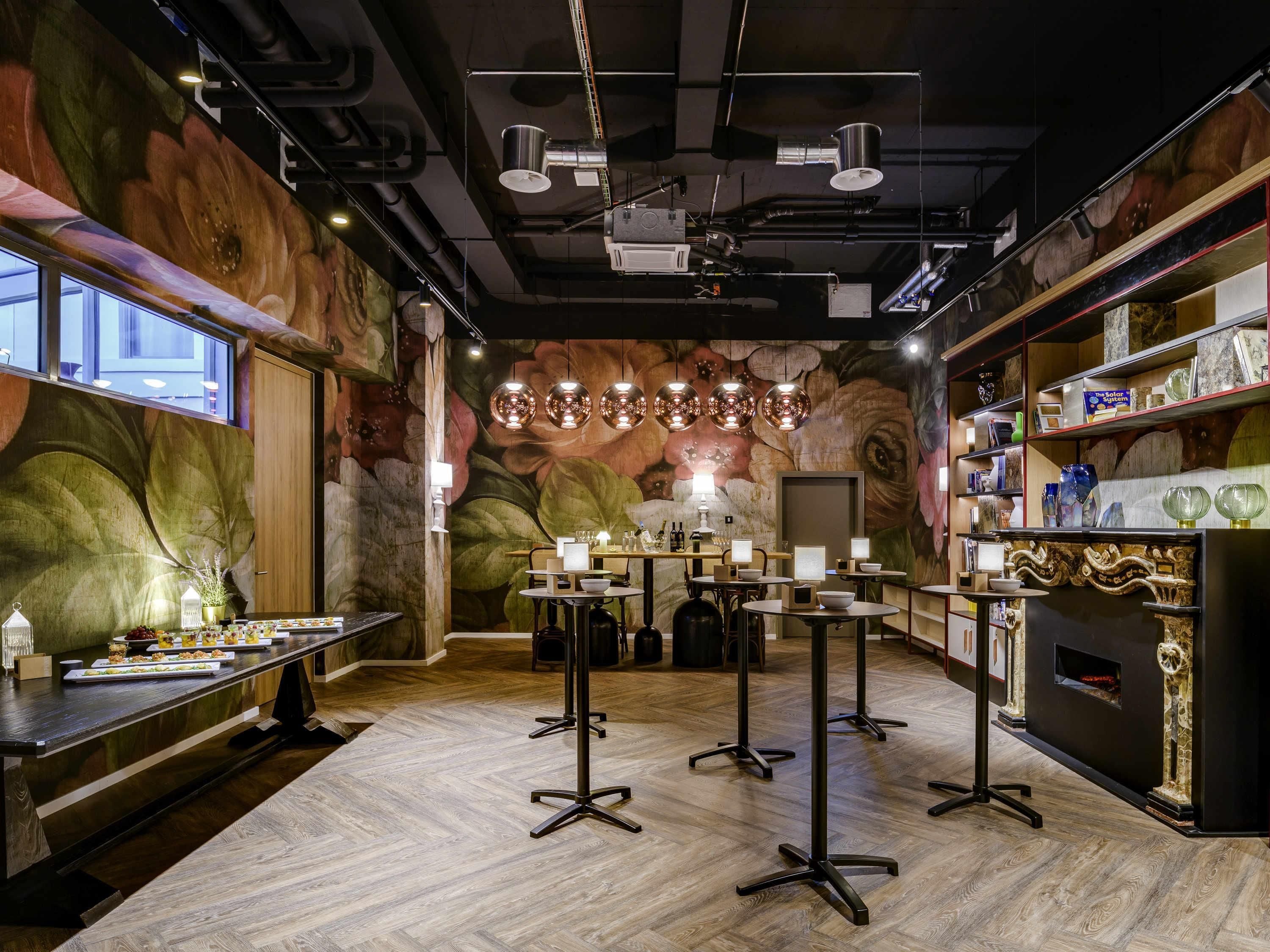 Un intérieur moderne avec un plancher en bois, des tables rondes et une fresque murale décorative.
