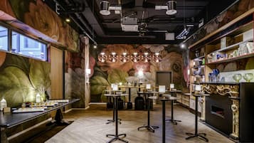 Un intérieur moderne avec un plancher en bois, des tables rondes et une fresque murale décorative.