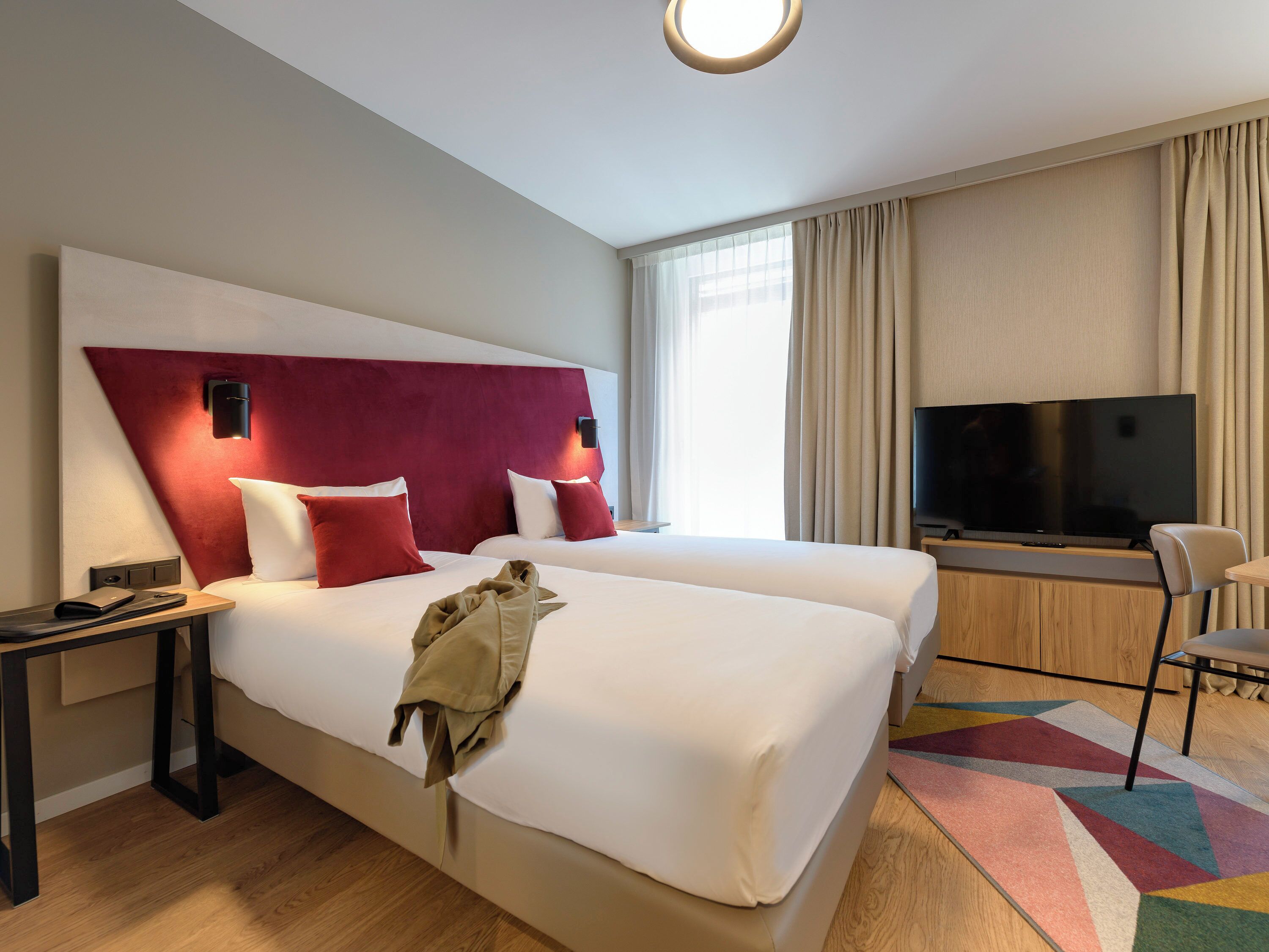 Habitación de hotel con dos camas, televisión, escritorio y una silla.