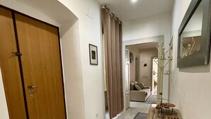 Un couloir avec une porte en bois, un miroir et une table sur laquelle se trouve un objet décoratif.