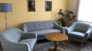 A room with a grey sofa, two armchairs, a round wooden table, and a potted plant. - Cozy vacation apartment in Dresden (Dresden)