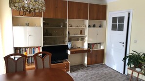 A dining area with a wooden table and chairs, a television, and built-in wooden cabinets with shelves. - Cozy vacation apartment in Dresden (Dresden)