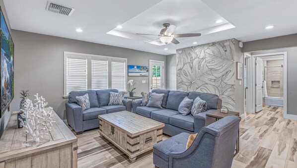 A modern living room with a sectional sofa, a coffee table, and a ceiling fan.