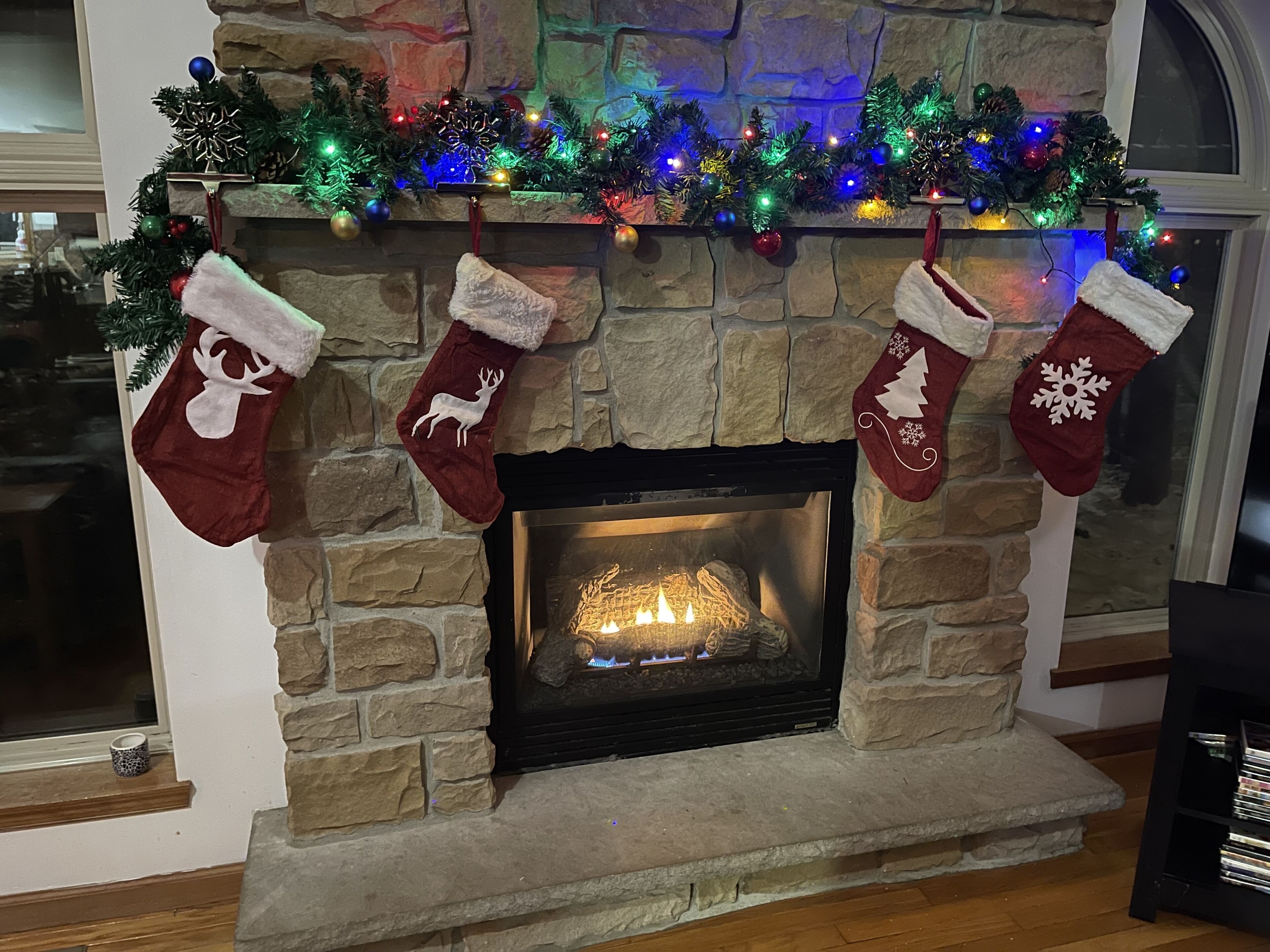 Ein Kamin aus Stein mit Weihnachtssocken und bunten Lichtern.