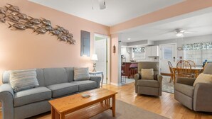 A living room with a sofa, armchairs, a coffee table, and a wall art piece.