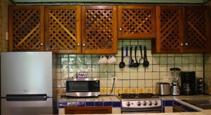 Kitchen features a traditional design with a gas stove, refrigerator, and microwave, along with a tiled backsplash and kitchen utensils on the wall.