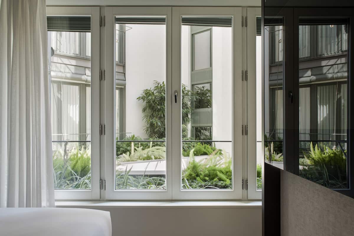 A room with a large window overlooking a balcony with plants.