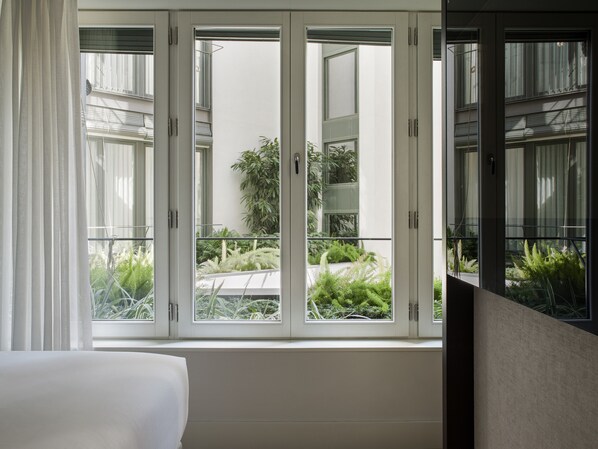 A room with a large window overlooking a balcony with plants.