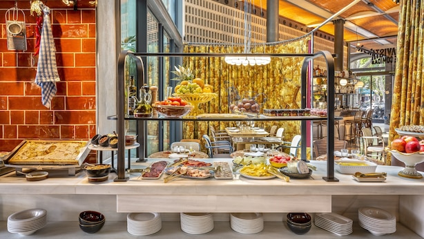 Buffet com diversos tipos de comida e um fundo de parede de tijolos.