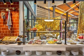 A buffet with various food items and a brick wall backdrop.