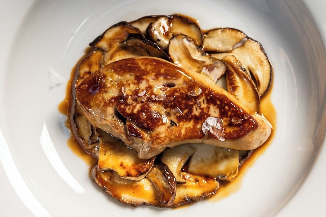 A plate of grilled chicken breast with mushrooms and sauce.
