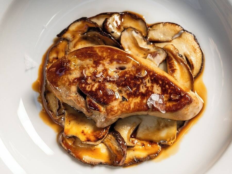 A plate of grilled chicken breast with mushrooms and sauce.