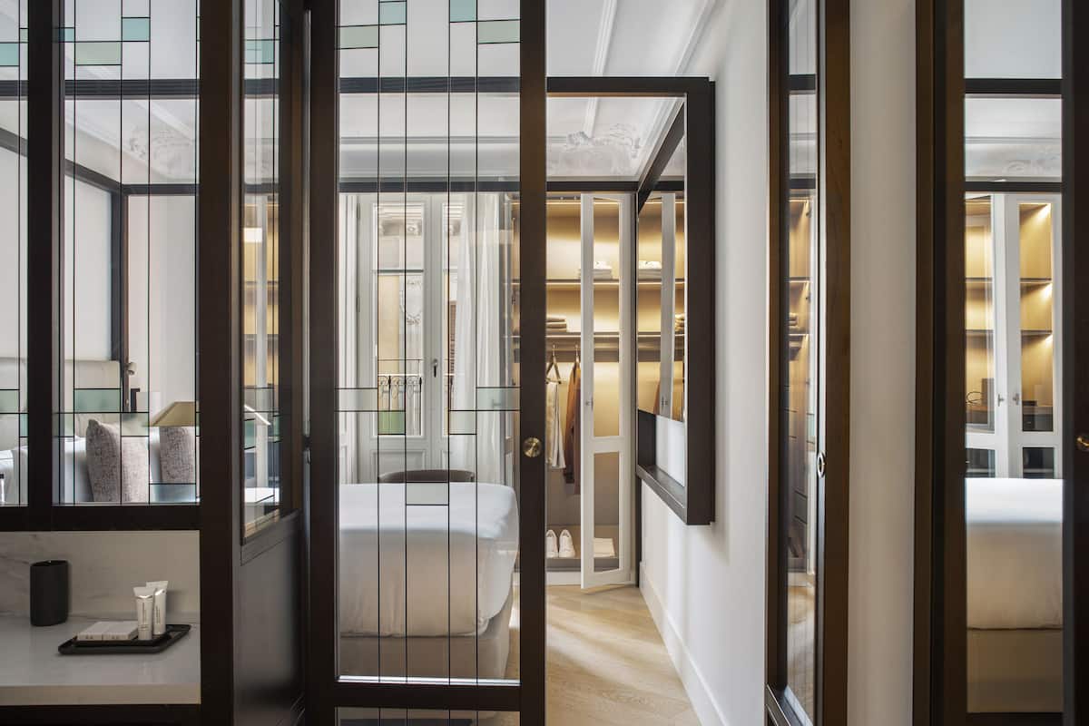 A hotel room with a bed, a desk with a tray of toiletries, and a closet with hanging clothes.