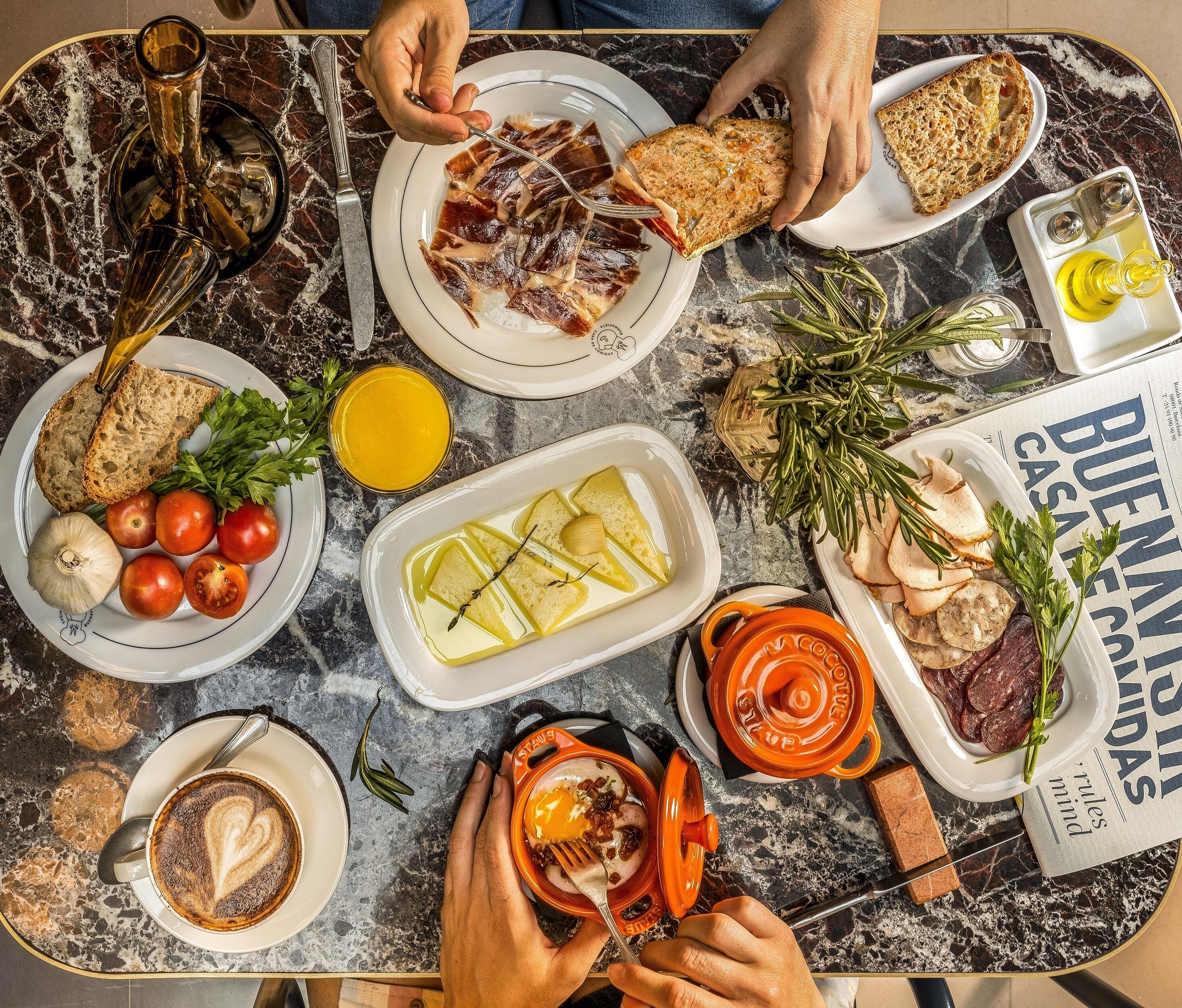 A table with various food items, including bread, tomatoes, and a dish with lemon slices.