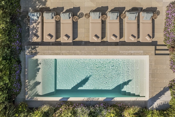 Una piscina al aire libre, sombrillas, sillones reclinables de piscina