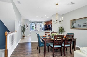 A dining area with a wooden table and chairs, a chandelier, and a view into the kitchen. - Pleasant and Spacious Town Home Near the Convention Center #3vc107 (Orlando)