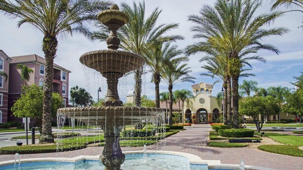 A fountain with multiple tiers and water jets, surrounded by palm trees and a well-maintained garden. - Pleasant and Spacious Town Home Near the Convention Center #3vc107 (Orlando)
