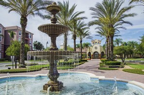 Stunning fountain surrounded by a tranquil pool and lush greenery, set against a classic building with arched windows.