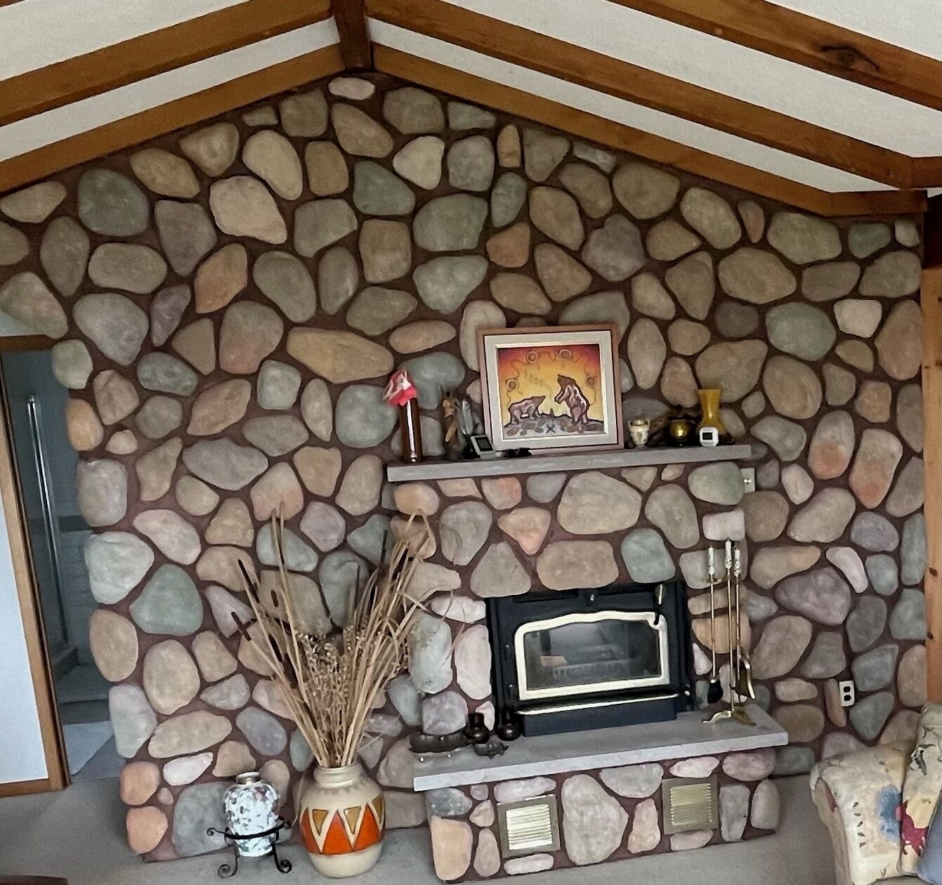 A stone fireplace with a mantel shelf, a framed picture, and decorative items.