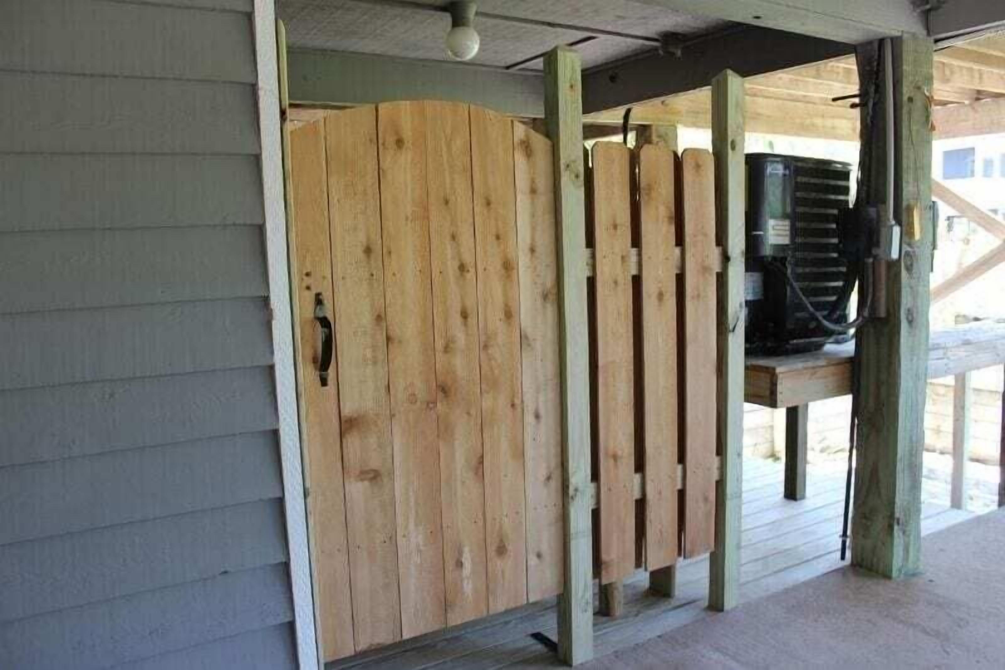 A wooden door with a handle, a wooden fence, and a black object on a wooden stand.