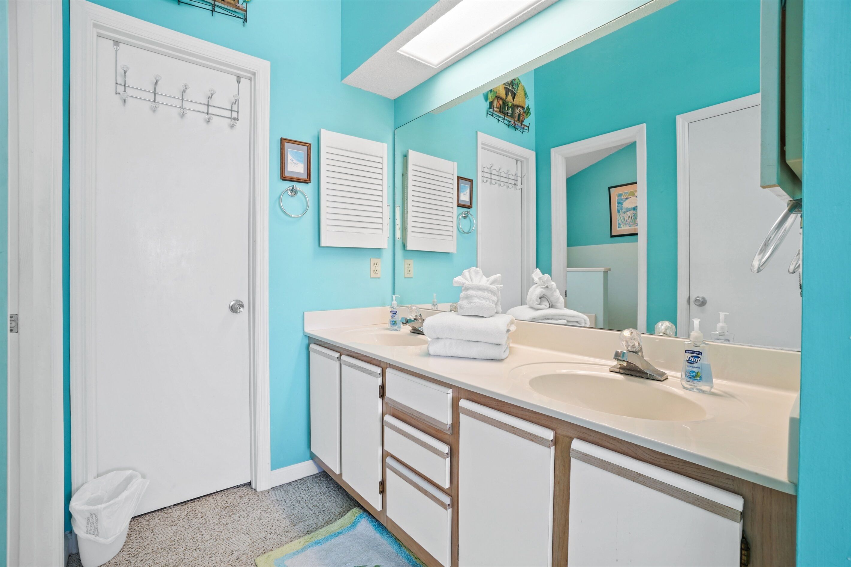 A bathroom with a turquoise wall, a white sink, and a mirror.