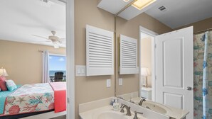 Une chambre avec un lit, une salle de bain avec un lavabo et un miroir, et une vue sur l’extérieur.