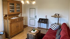 A living room with a wooden cabinet, a red sofa, a small table with a lamp, and a door with a green frame. - Vacation at the winery (Maring-Noviand)