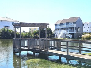 A wooden pier leading to a gazebo over water, with buildings in the background.