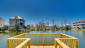 A wooden deck with a view of a calm lake, surrounded by buildings and trees. - Fall 2026 Rate Drop! Gulfview, 2 BR/2.5 BA, Great Location! (Port St. Joe)