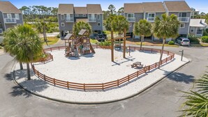 A playground with a wooden play structure, surrounded by a sandy area and a wooden fence. - Fall 2026 Rate Drop! Gulfview, 2 BR/2.5 BA, Great Location! (Port St. Joe)