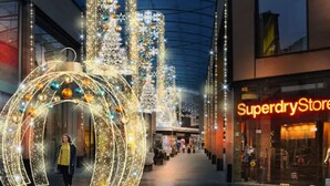 Un couloir d’un centre commercial, décoré d’illuminations de Noël, avec un magasin Superdry.