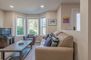 Relax in this stylish living room with a large window offering a view of the outdoors, a comfortable sofa, and a flat-screen television.