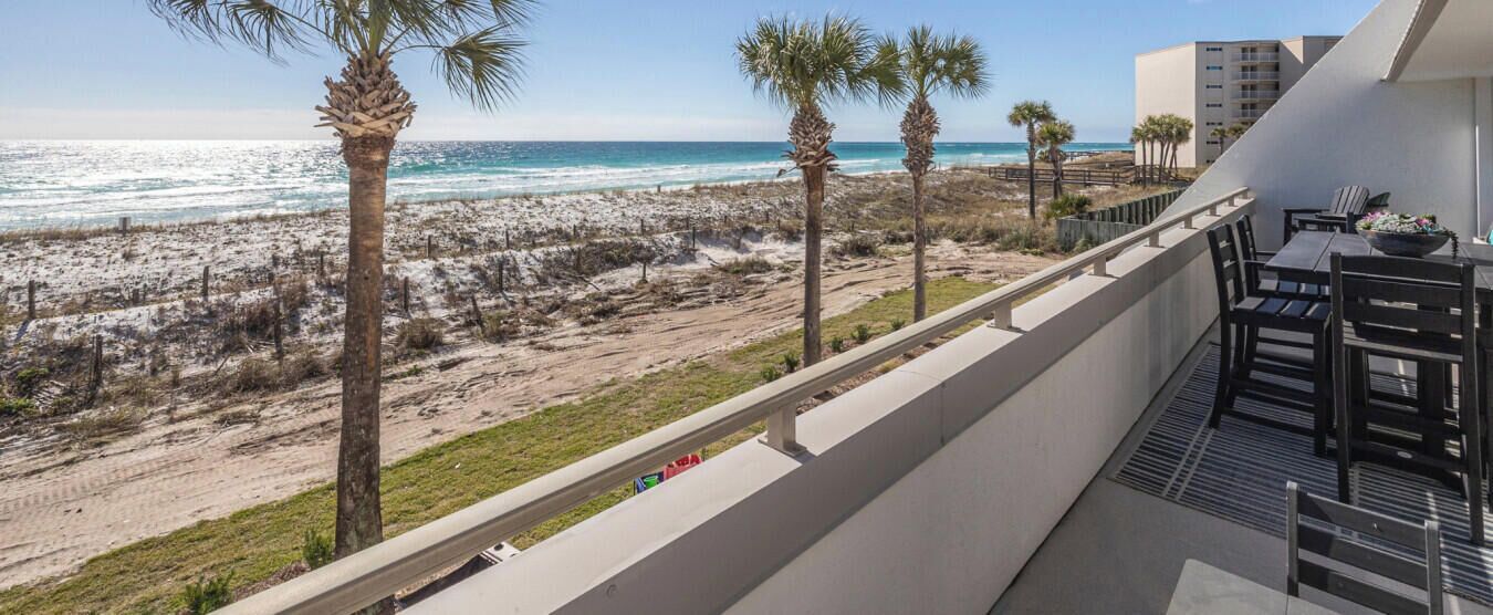 A balcony with a view of the beach and ocean.