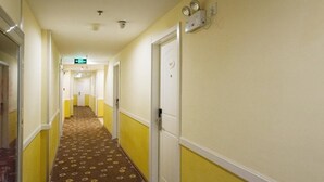 A hotel hallway with yellow walls, white trim, and patterned carpet.