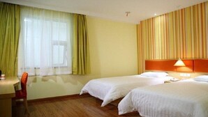 A hotel room with two beds, a desk, and a chair.